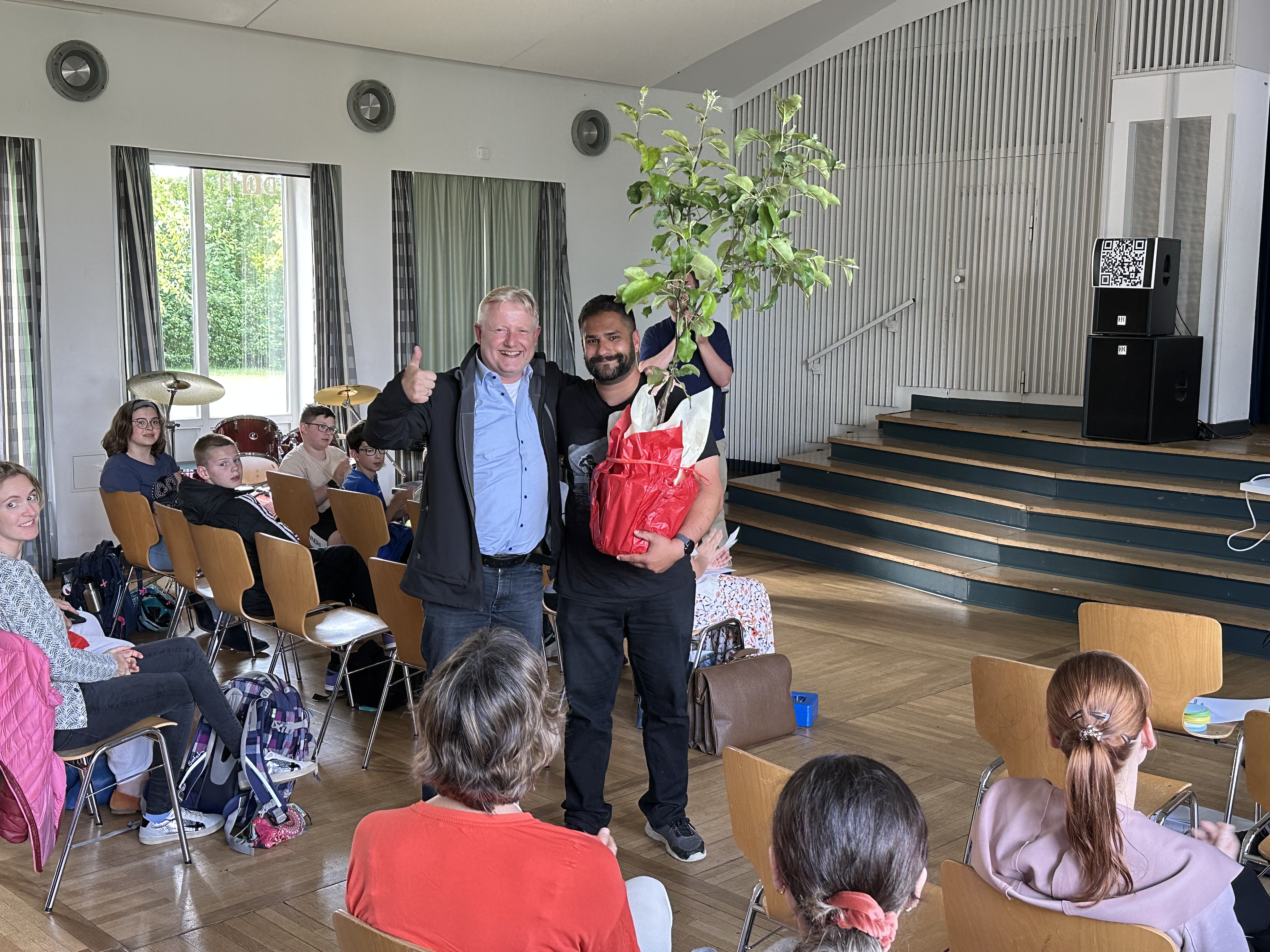 Bild: Thorsten Wendt (links) bekommt Apfelbaum von Fabian Shafiq (rechts), Bild von Nils Kanitz